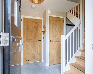 Entrance to Villa Jolie in De Koog, Texel, with wooden doors and stairs to upper floor.