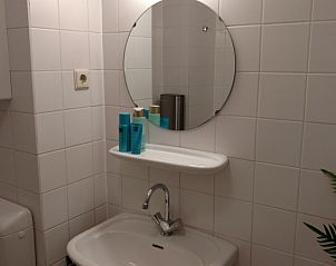 Stilvolles Badezimmer in De Pelikaan Apartments, De Koog, Texel mit modernem Waschbecken und Spiegel.