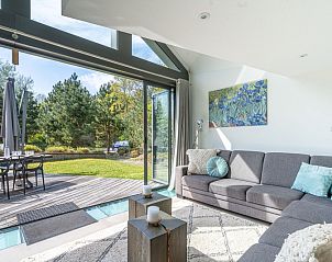 Spacious living room in Duynzoom Villa 5, a vacation home in De Koog, Texel, with large windows and garden views.