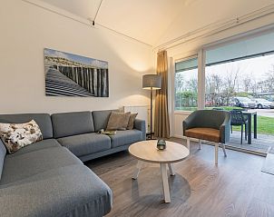 Gezellige woonkamer in T4M Comfort bungalow, De Koog, Texel. Comfortabele zitruimte met uitzicht op de groene tuin en natuurlijke omgeving.