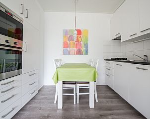Moderne Kche in 't Kerckeland - Appartement Kerckeland 88, De Koog, Texel mit Esstisch, bunter Kunst und kompletter Ausstattung.