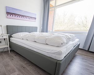 Schlafzimmer in 't Kerckeland - Apartment Kerckeland 88, De Koog, Texel mit bequemem Bett und groem Fenster mit Blick auf die Umgebung.