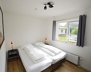 Ferienhaus Stappeland 203 in De Koog Texel, helles Schlafzimmer mit Doppelbett und Gartenblick.