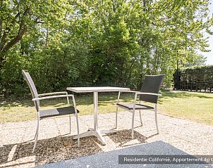 Sunny terrace at Type 4 vacation home, De Koog, Texel. Perfect for outdoor dining amidst nature.