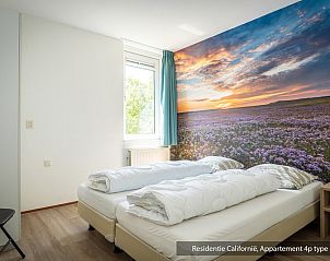 Schlafzimmer in einer Unterkunft des Typs 5A, De Koog, Texel, mit zwei Betten und bunter Landschaftstapete.