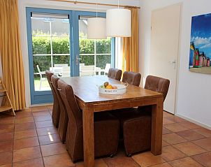 Gezellige eetkamer in bungalow T8A, De Koog, Texel met houten tafel en tuinzicht, ideaal voor een ontspannen verblijf op de Waddeneilanden.