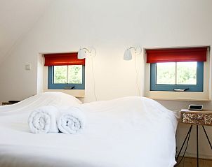 Sfeervolle slaapkamer in bungalow T8A, De Koog, Texel met comfortabele bedden en rustgevende natuuruitzichten door de ramen.