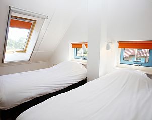 Sfeervolle slaapkamer in bungalow T8A, De Koog, Texel met comfortabele bedden en dakraam voor natuurlijk licht op de Waddeneilanden.