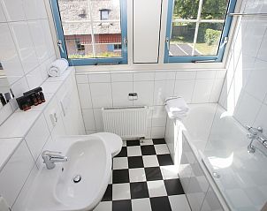 Moderne badkamer in bungalow T8A in De Koog, Texel, Waddeneilanden met helder daglicht en stijlvolle zwart-witte tegelvloer.