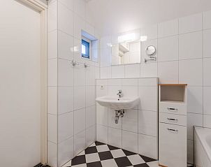 Moderne badkamer in bungalow T6AB, De Koog, Texel, met strakke witte tegels en stijlvolle wastafel voor ultiem comfort op de Waddeneilanden.