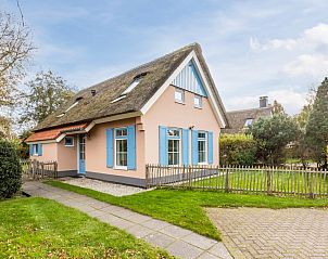 Charmante bungalow T6AB met rieten dak in De Koog, Texel, omringd door groene tuin en rustieke hek, ideaal voor een ontspannen vakantie op de Waddeneilanden.