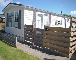 Chalet Bregkoog 255 in De Koog, Texel with sunny veranda and wooden fence, ideal for a relaxing vacation on the Wadden Islands.