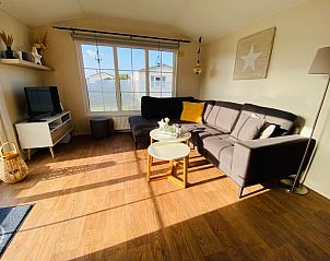 Cozy living room of Chalet Bregkoog 255 in De Koog, Texel with comfortable sofa and lots of natural light, ideal for relaxation.