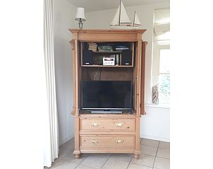 Wooden cabinet in Pauwenhof Texel, De Koog with TV and audio equipment for relaxation.