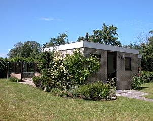 Bungalow Oud Vredelust 75 in De Koog, Texel, surrounded by green nature and flowers.