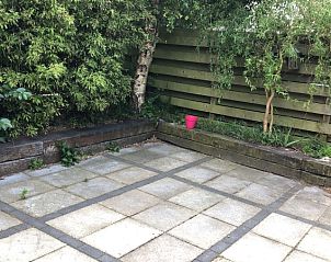 Quiet garden environment at vacation home Kamerstraat 39, De Koog, Texel with green plants and wooden fence.