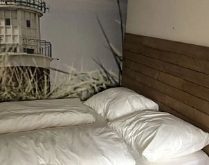 Bedroom in vacation home Kamerstraat 39, De Koog, Texel with comfortable beds and attractive wall coverings.