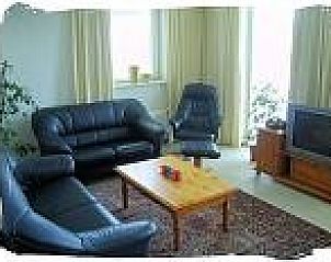 Gezellige woonkamer in vakantiewoning De Koog, Texel, met comfortabele leren banken en veel natuurlijk licht.