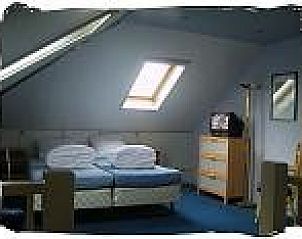 Ruime zolderkamer met dakraam in vakantiewoning De Koog, Texel, biedt extra slaapruimte en comfort.