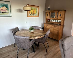 Dining area in Stormvogel, vacation home in De Koog, Texel with round table and wooden cabinet.