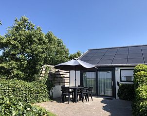 Spacious terrace at Bungalow 2 in De Koog, Texel with comfortable seating surrounded by green nature.