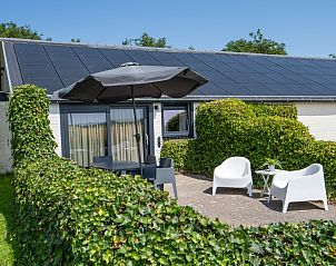 Cozy terrace with seating at Bungalow 2, vacation home in De Koog, Texel, surrounded by greenery.