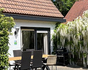 Terrace of Koetshuis 3 vacation home in De Koog, Texel with dining table and green planting.