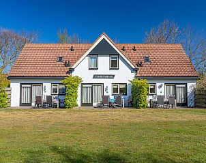 Front view of Koetshuis 3 vacation home in De Koog, Texel with terrace and green surroundings.