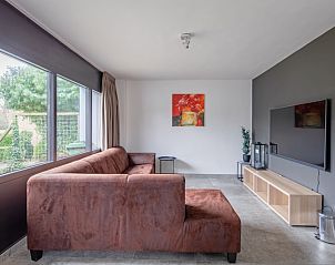 Comfortable sitting area in Orchismient 20, vacation home De Koog, Texel, with large windows and garden view.