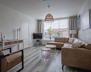 Helles Wohnzimmer des Ferienhauses Schoonoord in Den Burg, Texel, mit groen Fenstern und modernen Mbeln.