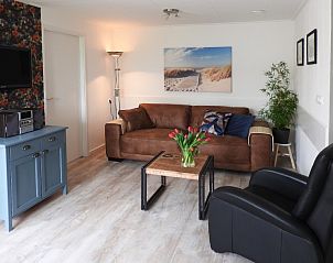 Gezellige woonkamer in familie Smit bungalow Den Burg Texel met comfortabele bank en decoratieve kunst.