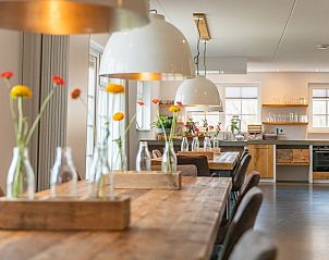 Gezellige eetruimte in Groepsverblijf Nieuw Leven 24p, Den Burg, Texel, met landelijke tafels en bloemen.