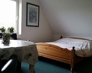Gezellige slaapkamer in B&B van der Wal, Den Burg Texel, met houten bed en uitzicht op de natuur van de Waddeneilanden.