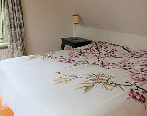 Comfortable bed in The Achterhuys vacation home on Texel with window view.