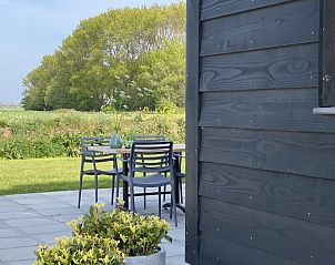 Terras van Villa Nieuw Leven Texel, vakantiehuis in Den Burg, met uitzicht op groene velden.