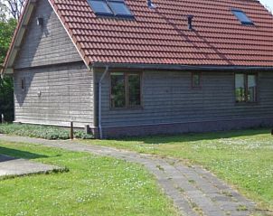 Zijaanzicht van Vakantiehuis Duinzicht in Den Burg Texel met rode dakpannen en grasveld.