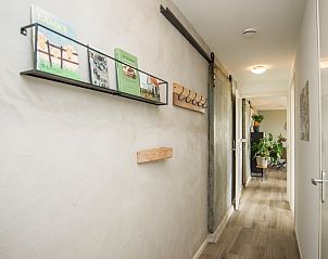 Stijlvolle gang in Onder de Wol vakantiehuis Texel met boekenplank en kunst.