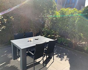 Schaduwrijk terras van vakantiehuis 4780 - Van der EL in Den Hoorn, Texel met tuinmeubilair en groene haag.