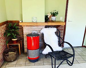 Knusse hoek met haard en stoel in Vakantiehuis Vogelsand, Den Hoorn Texel, ideaal voor ontspanning.