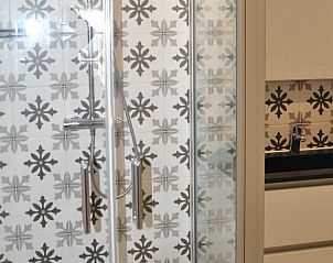 Moderne badkamer in Vakantiehuisje Den Hoorn Texel met stijlvolle tegels en douche.