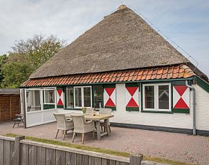 Buitenzicht van Appartement Heem, een charmante vakantiewoning in Den Hoorn, Texel, met traditioneel rieten dak en gezellige veranda.