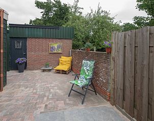 Privterras van vakantiehuis 3685, Oosterend Texel, met zitgelegenheid en groene omgeving.