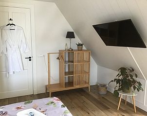 Moderne faciliteiten in De Borage Texel, Oosterend, met een flatscreen-tv en stijlvolle houten meubels voor een comfortabel verblijf.