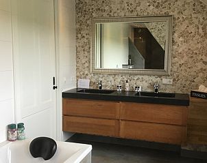 Stijlvolle badkamer in De Borage Texel, Oosterend, met grote spiegel en moderne wastafels voor optimaal comfort.