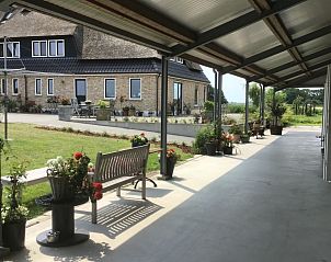 Veranda van De Borage Texel, Oosterend, met gezellige zitjes en uitzicht op de groene omgeving voor ontspanning in de buitenlucht.