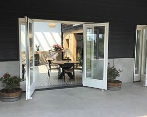 Toegang tot de lichte eetruimte van De Borage Texel, Oosterend, met open deuren en veel natuurlijk licht.