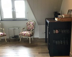 Comfortabele zithoek in De Borage Texel, Oosterend, met klassieke stoelen en een minibar voor een luxe verblijf.