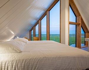 Schlafzimmer im Ferienhaus in Oosterend, Texel mit groen Fenstern und Blick auf die Landschaft.