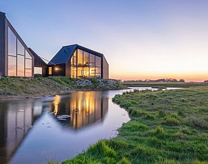 Ferienhaus in Oosterend, Texel bei Sonnenuntergang mit Spiegelung im Wasser, Wadden Islands.