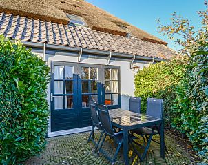 Terrasse des Ferienhauses in Oosterend, Texel, Ferienhaus mit Tisch im Freien, umgeben von Grn auf den Watteninseln.